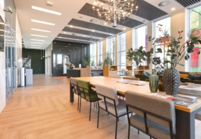 Moderne kantoorruimte aan de Barbara Strozzilaan met grote ramen, houten vloer en een lange vergadertafel.